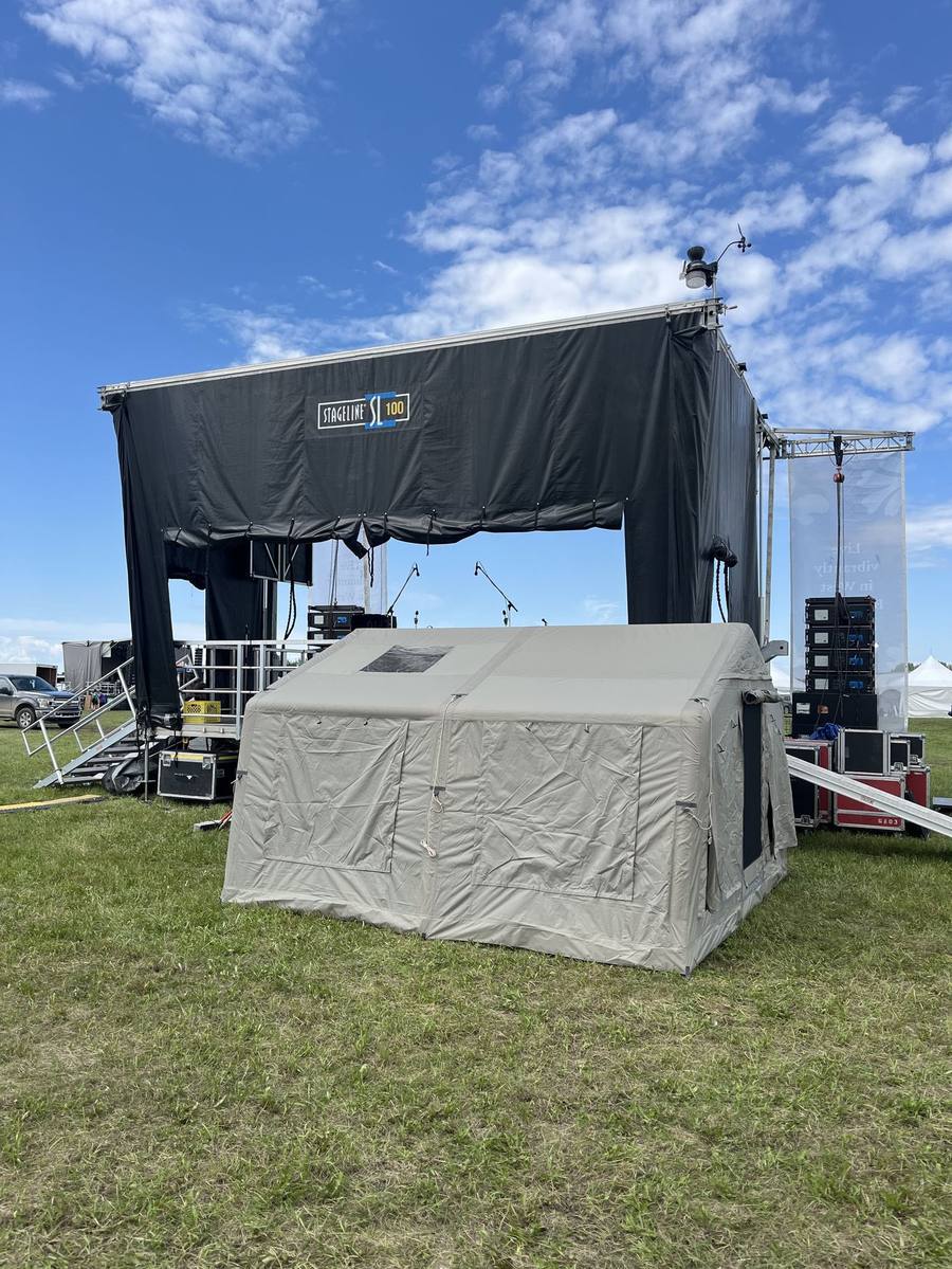 K1 Outdoors tent set up on the grass in front of a festival stage