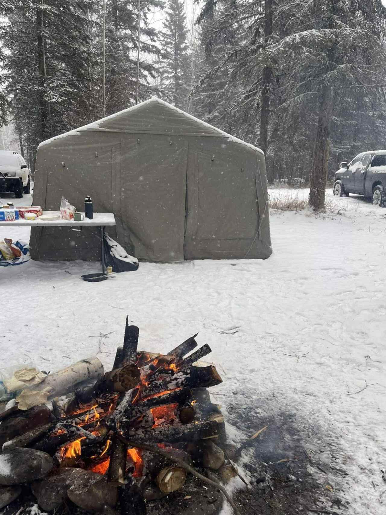 K1 Outdoors tent in snowfall next to a campfire